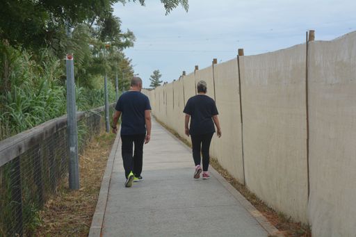 A back view of a beautiful couple walking on a road under the cloudy sky