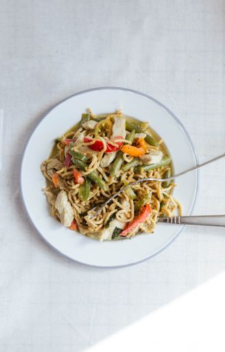 A vertical high angle shot of a plate of delicious vegetable noodles on a white surface