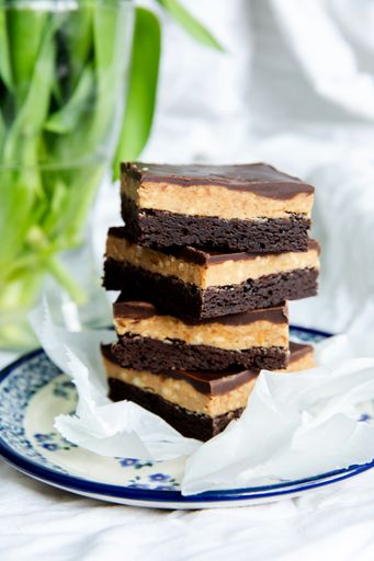 A vertical shot of pieces of delicious chocolate cake on a plate near a flower vase