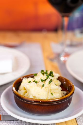 A vertical shot of mashed potatoes in a bowl in a restaurant