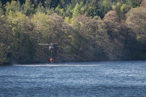 Firefighting helicopter collecting  water from the lake to extinguish forest fire