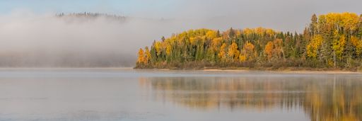 A panoramic view of a lake reflecting the autumn trees on the shore, Canada