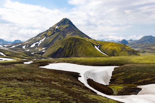 The mossy green mountains with patches of snow on the Laugavegur trekking trail near Landmannalaugar and Porsmork