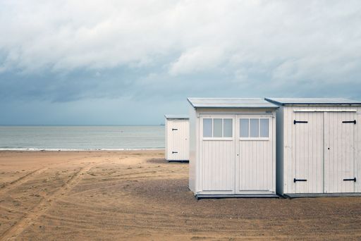 A beautiful shot of white small rooms on a beach shore near the water under a cloudy sky