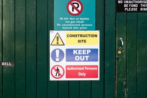 A closeup shot of a "Construction Site, Keep Out and Authorised Persons only" phrase on a sign  on a green wooden wall