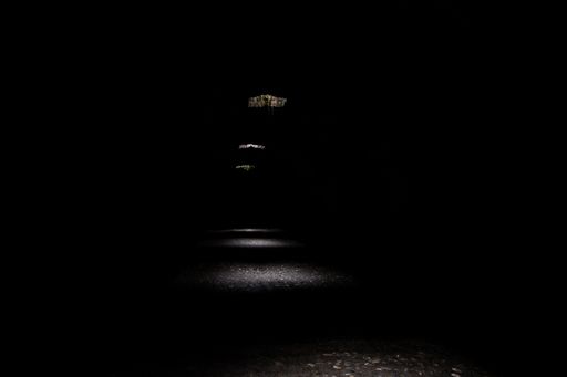 A horizontal shot of a dark tunnel with daylight entering through the holes creating a mysterious image