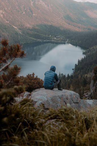 A male traveler hiking on a high rock and enjoy with mountains and cloudy sky