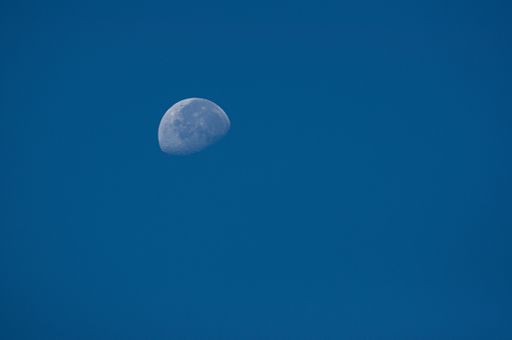 A close up of half moon during daylight with blue sky background