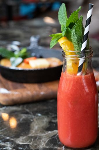 A vertical selective focus shot of a bottle of fresh smoothie with mint and lemon on a stone table