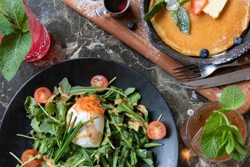 A high angle shot of a plate of delicious salad near some drinks on a black table