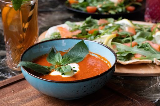 A high angle shot of a bowl of tomato soup and a plate of fresh salad on a table
