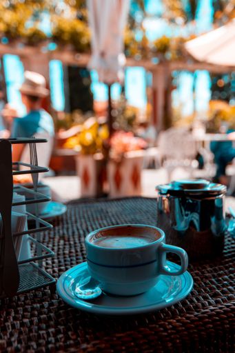 A shallow focus shot of a cup of coffee on a wicker table in a cafe with blurred background