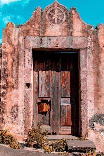 A vertical shot of an old wooden door under a blue sky in Funchal , Madeira, Portugal