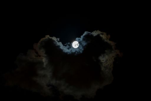 A beautiful night skyscape of the full moon glowing behind clouds