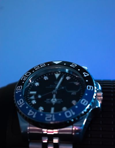 A vertical closeup shot of a Rolex watch with a blue background