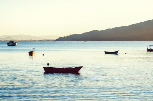 A beautiful shot of empty boats on the sea with a mountains and a bright sky in the background