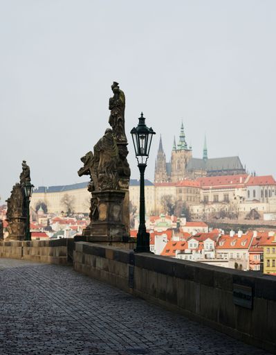 A vertical shot of the Statue on Charles Bridge, Prague, the Czech Republic, with a cityscape view in the background