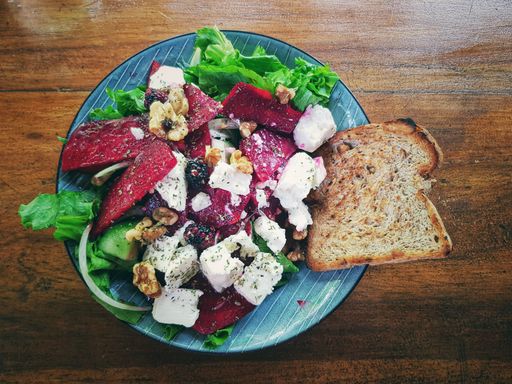 A top view of a delicious salad with cheese, vegetables, and a slice of bread on the wooden table