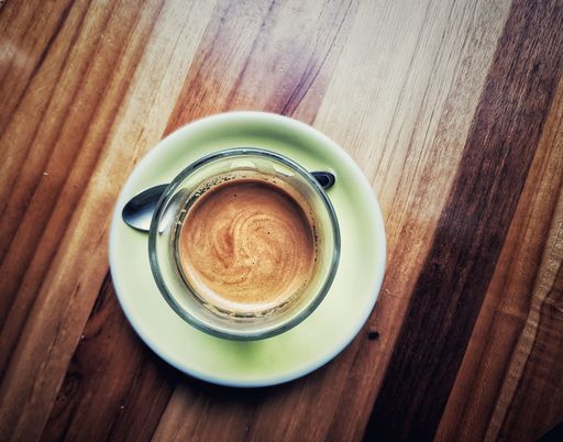 A vertical top view of a cappuccino cup on the wooden table