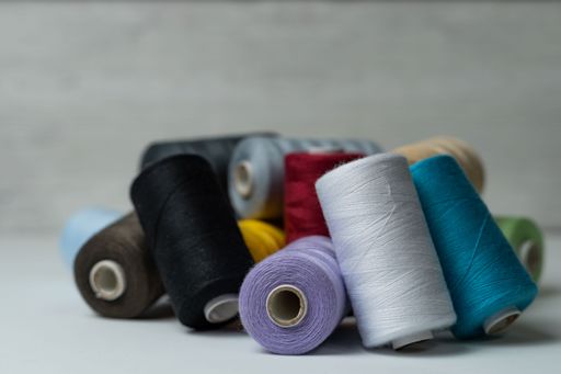 spools of colored sewing thread on white background with copy space
