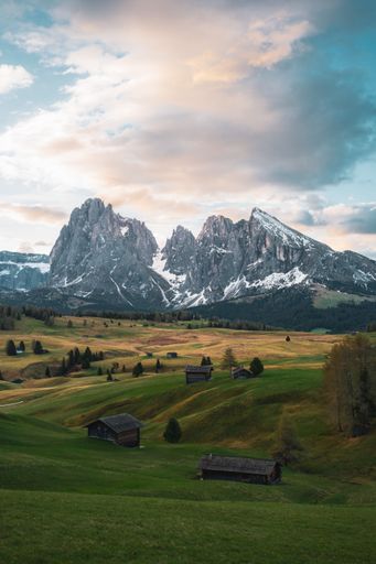 A vertical shot of the beautiful Alpine meadow surrounded with snow covered mountains in Italy