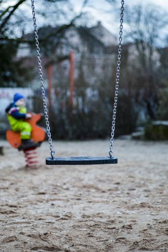 A vertical shot of a swing on a playground in a children's park