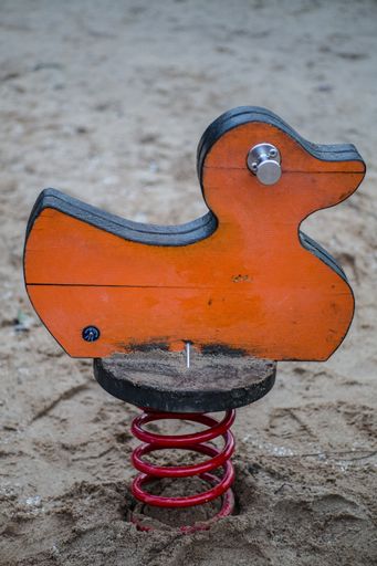 A vertical shot of a wooden duck on a playground