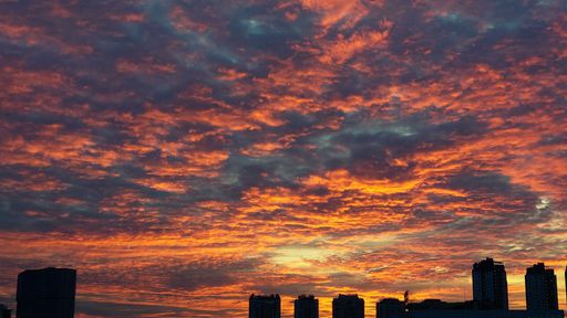 A beautiful view of a cloudy sky during orange sunset over buildings