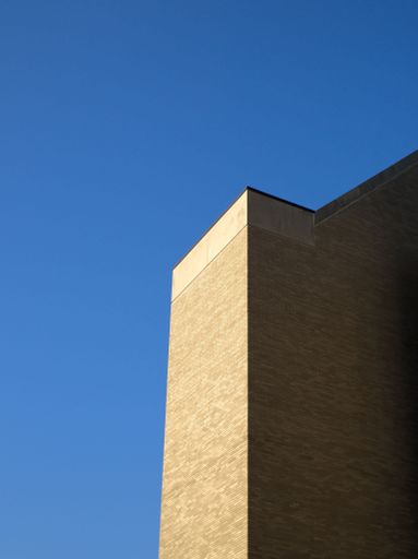 A minimalistic shot of a brick building illuminated by the sun at golden hour with a blue sky in the background.