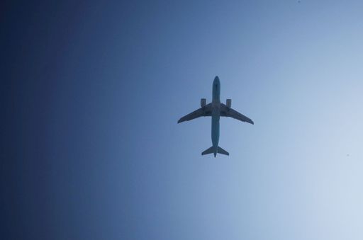 A low angle shot of an airplane flying in the air against a blue sky