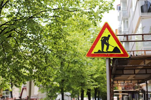A road construction sign on the street with trees in the background