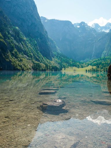 A beautiful scenery of a lake surrounded by high rocky mountains and greenery in Berchtesgaden National Park, Ramsau, Germany