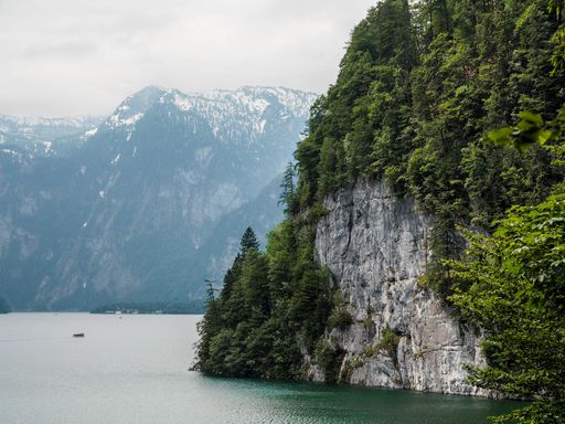 A beautiful scenery of a lake surrounded by high rocky mountains and greenery in Berchtesgaden National Park, Ramsau, Germany