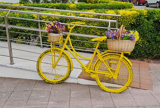yellow bicycle decorated with baskets of colorful flowers