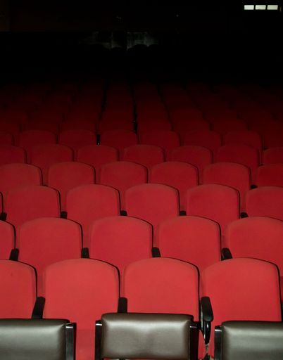 Some empty red chairs in a theater. Photo taken using flash light.