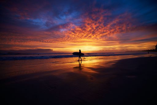A silhouette of surfer in the background of vibrant sunset scenery, Nosara peninsula, Costa Rica
