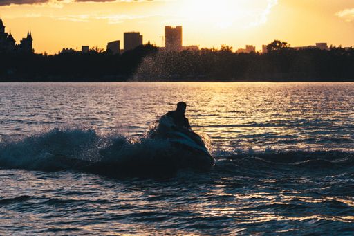 The silhouette of the man riding a jet ski at sunset