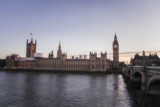 A vertical shot of the Big Ben tower and the House of Parliament behind the river Thames in London