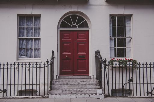 typical London house entrance with the red door, it has a small fence with flowers