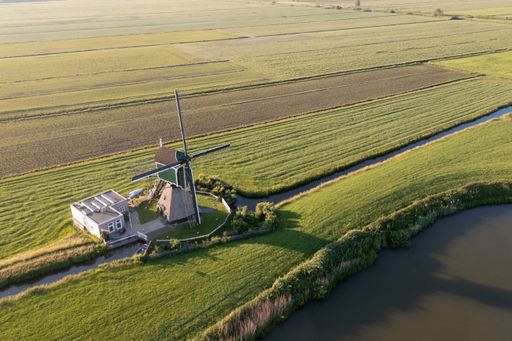 An aerial shot of a windmill in the middle of farm fields