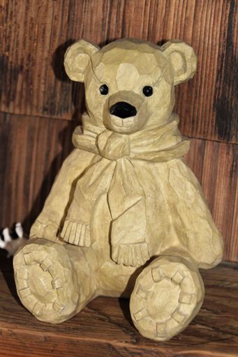A detailed carved wooden bear with a scarf