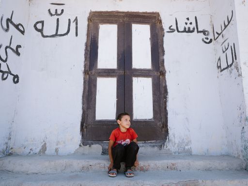 A young boy sitting alone in front of his home in Burullus, Egypt
