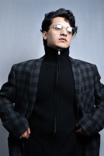 A beautiful shot of an Asian male wearing glasses and a checkered jacket