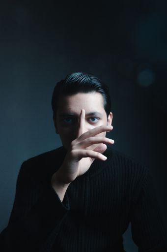 A vertical shot of an Asian male wearing a black sweater