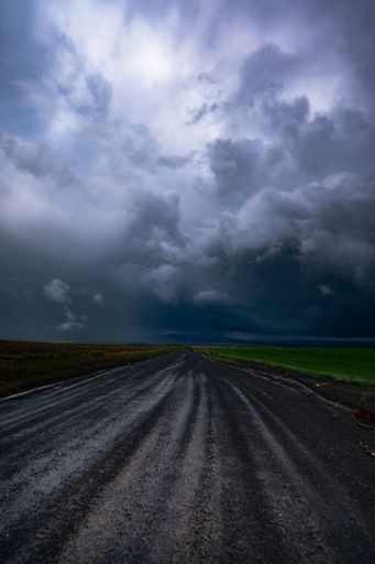 A vertical shot of dirt road under a dramatic gloomy sky