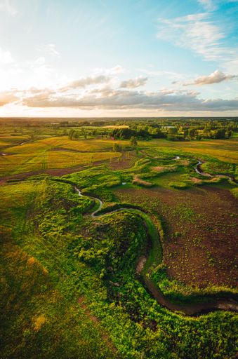 A vertical aerial view of landscape fields in springtime under  cloudy sky,