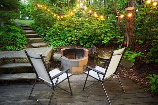 A beautiful shot of white chairs in front of a fireplace in a garden
