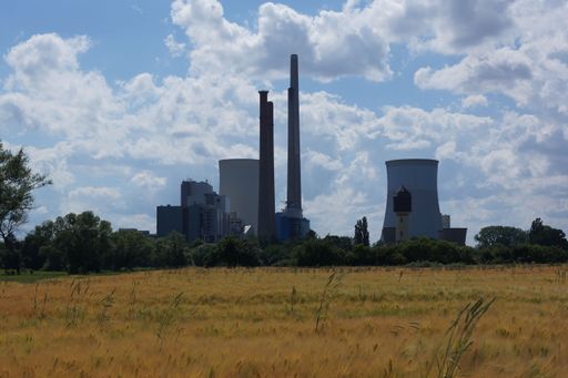 Silhouette of the Staudinger coal-fired power plant near Hanau, Germany, behind a grain field. Step by step decommissioned. Blue-white sky.