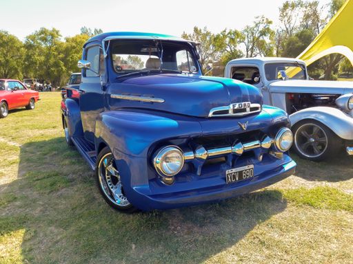Old blue Ford F 1 V8 1950s utility pickup truck in the countryside. Front view. Nature grass and trees. Classic car show. Copyspace.