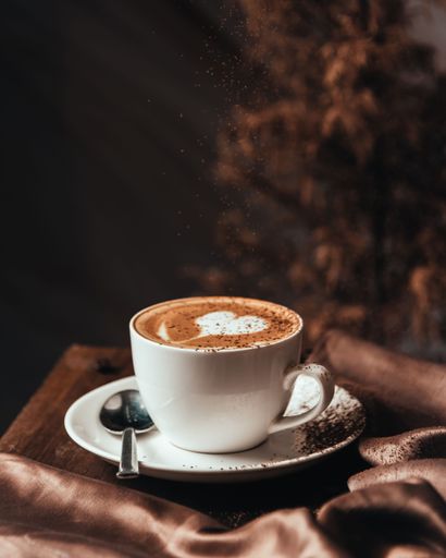 A vertical close-up shot of a beautiful cup of cappuccino with romantic latte art.